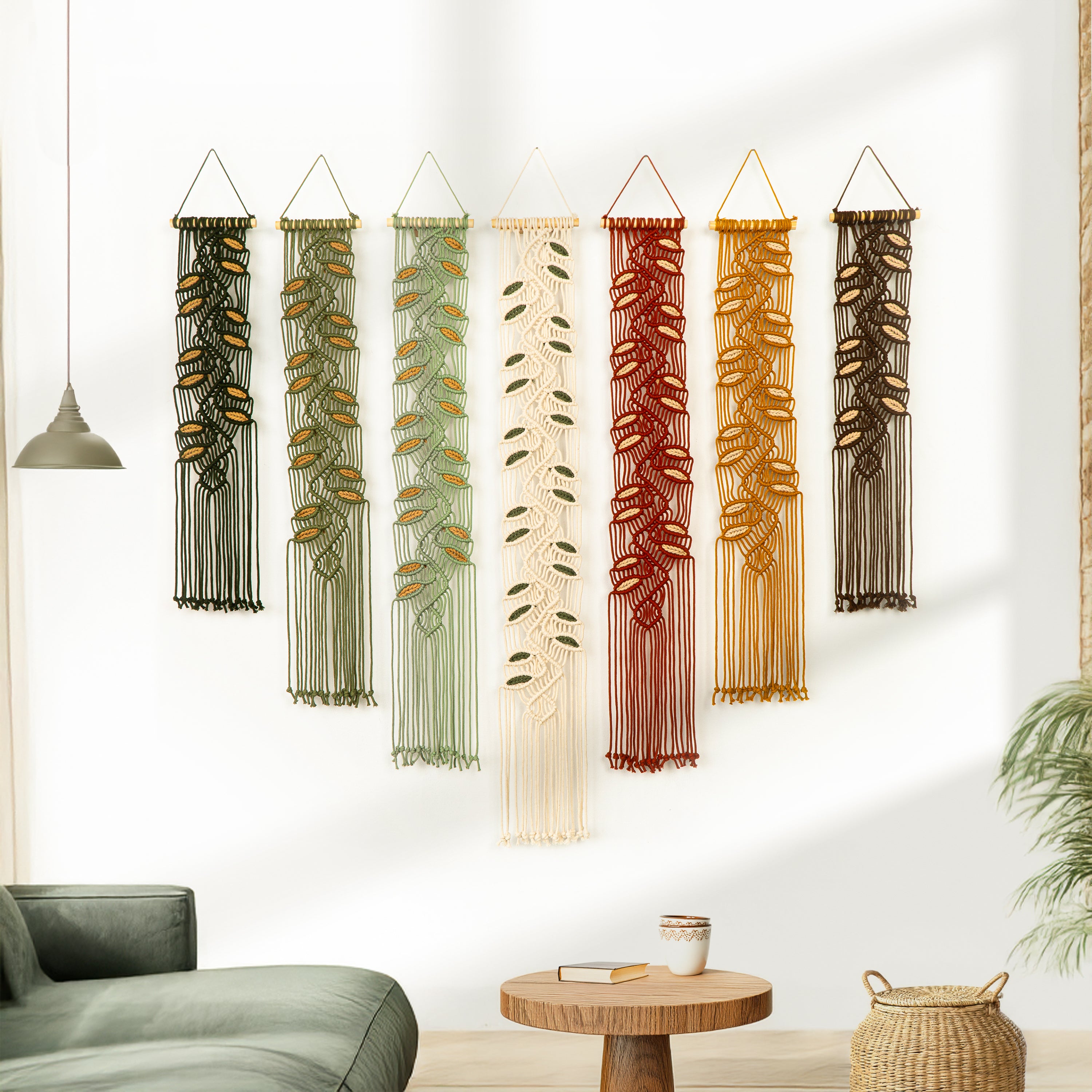 Set of four wall hangings with different designs on a white wall above a brown sofa.