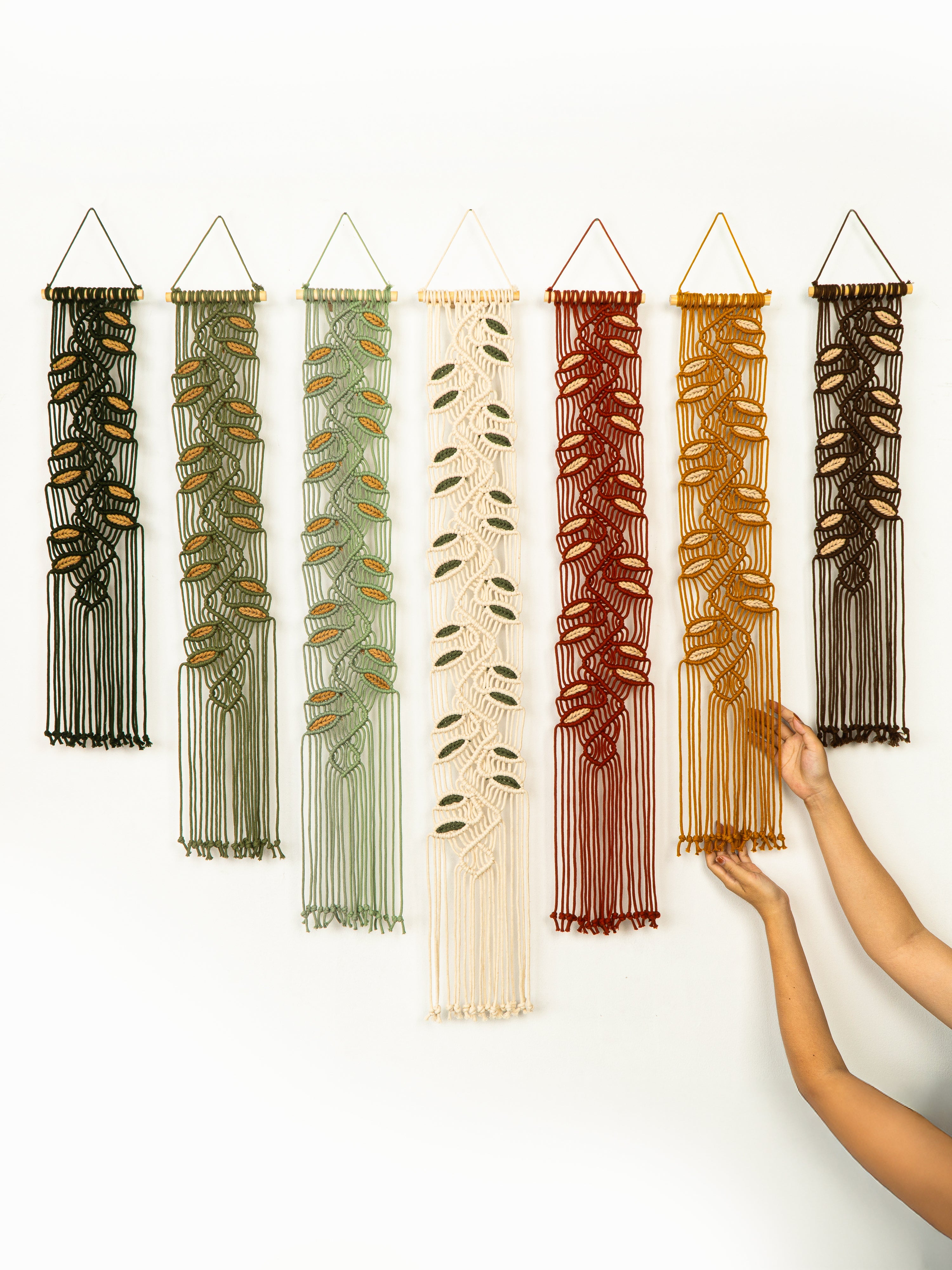 Set of six decorative wall hangings with leaf patterns in various colors on a white background.