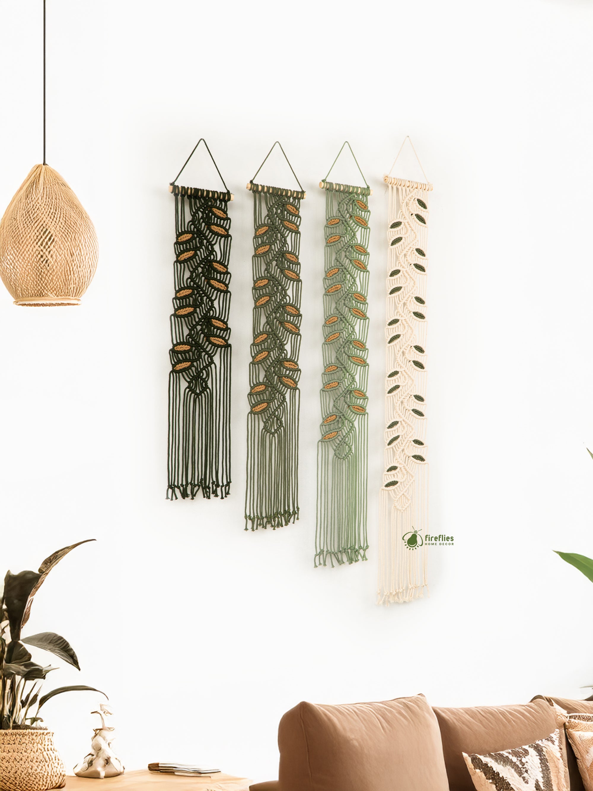 Four macrame wall hangings in different colors hanging on a white wall.