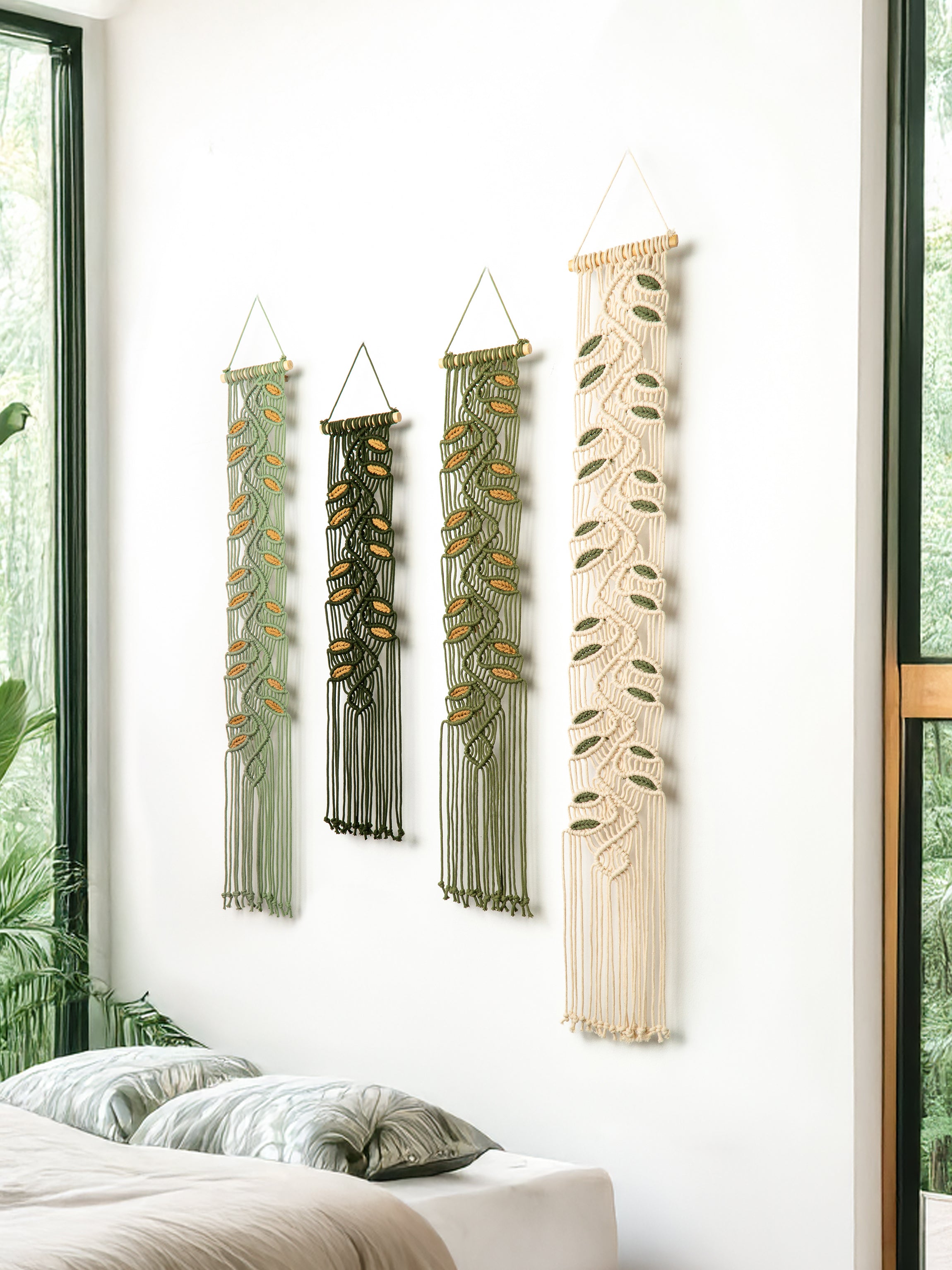 Four macrame wall hangings of varying designs on a white wall.