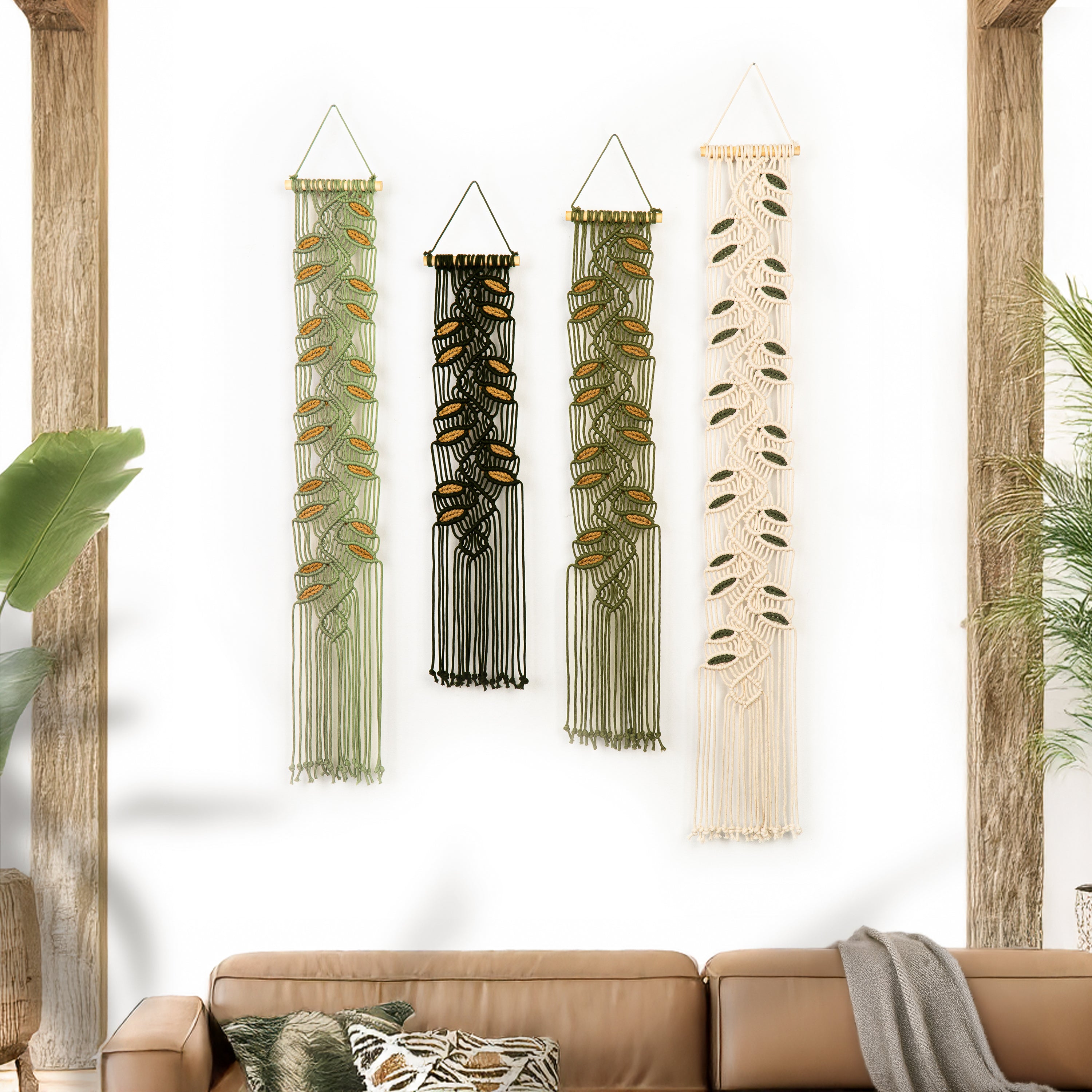 Set of four wall hangings with different designs on a white wall above a brown sofa.