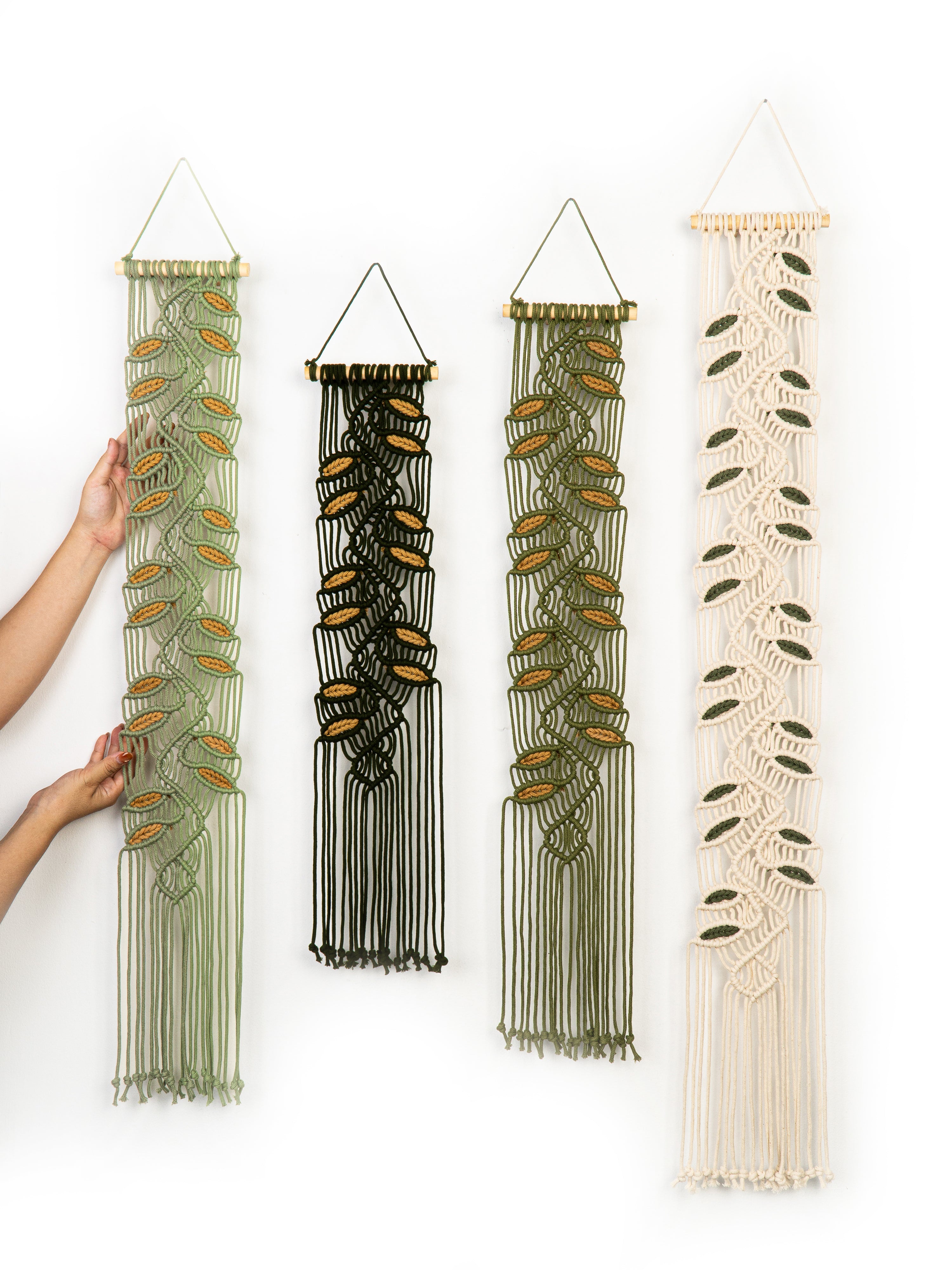 Four macrame wall hangings with different patterns on a white background