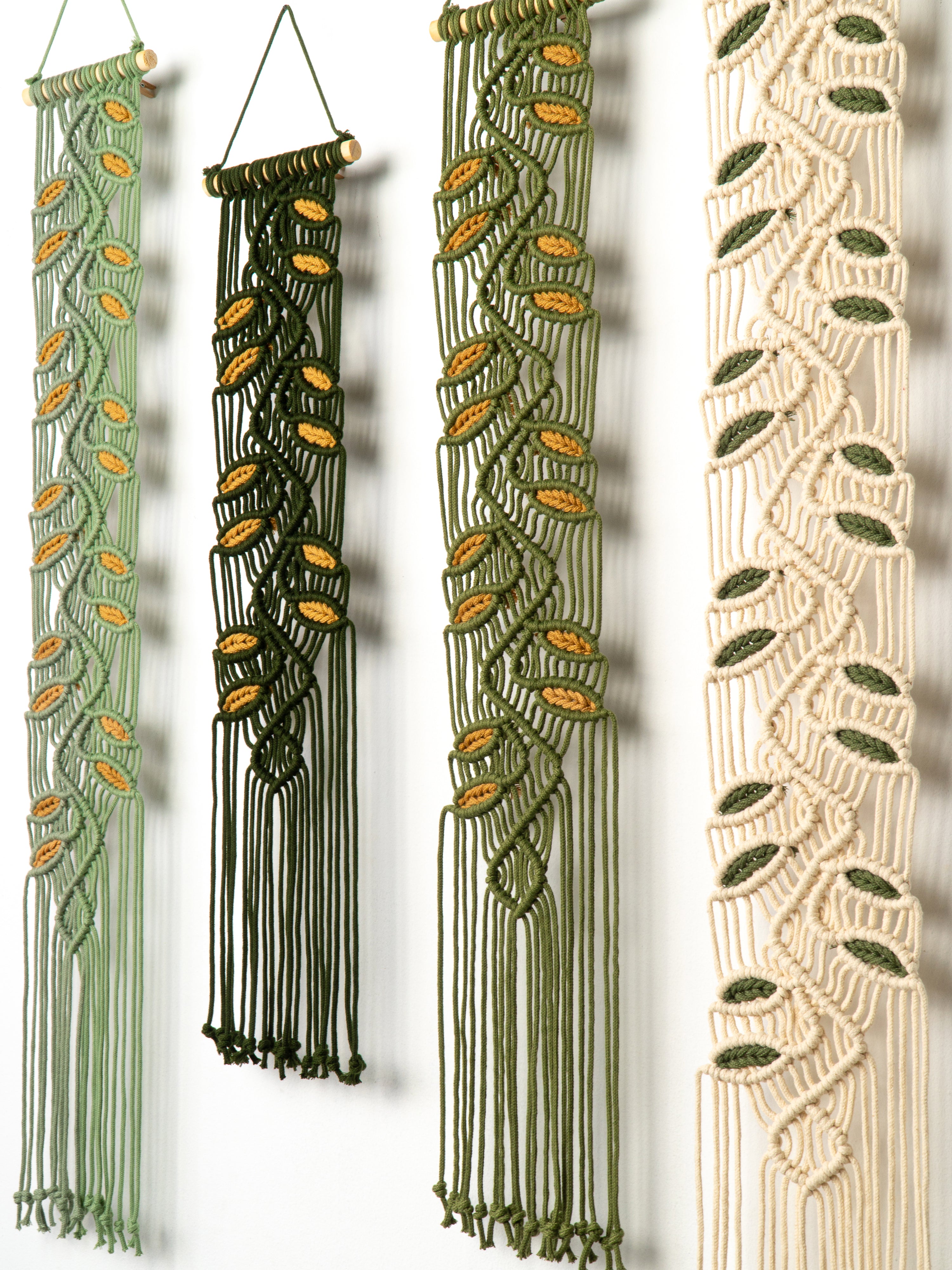Four macrame wall hangings with leaf patterns on a white background