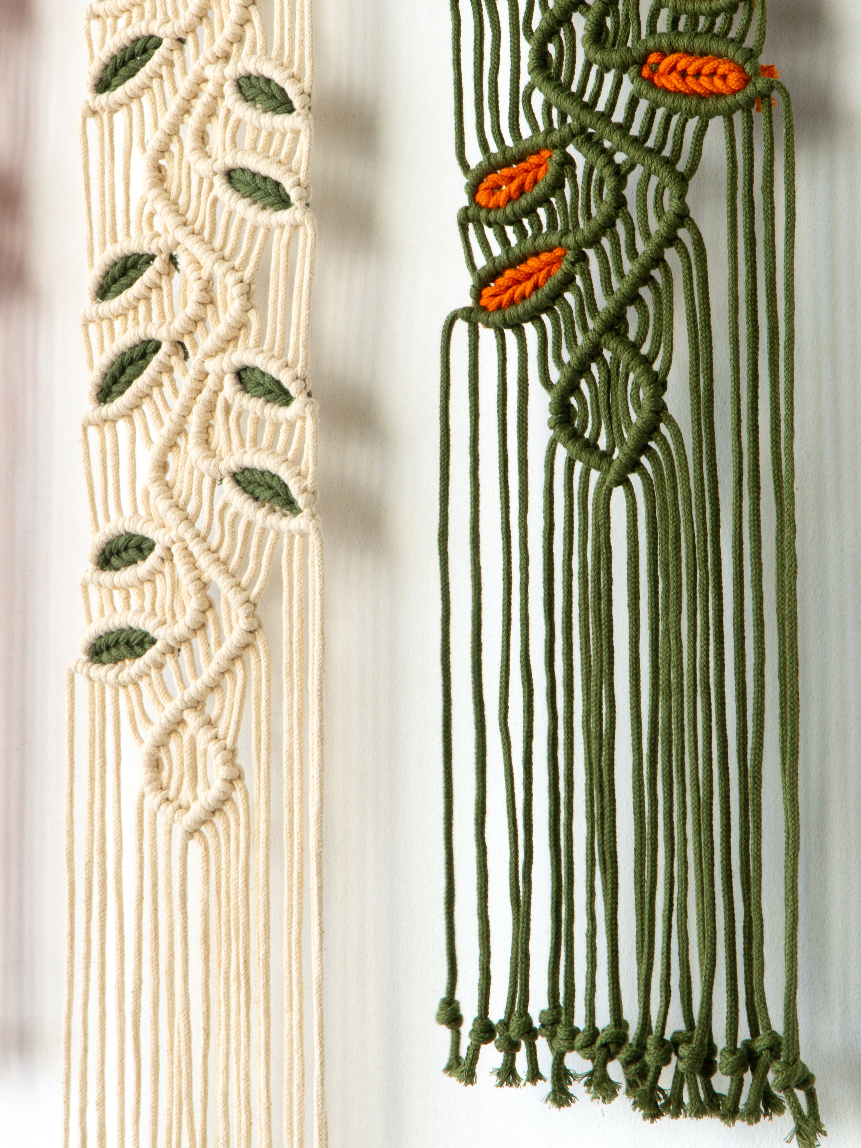 Two macrame wall hangings with leaf patterns on a neutral background