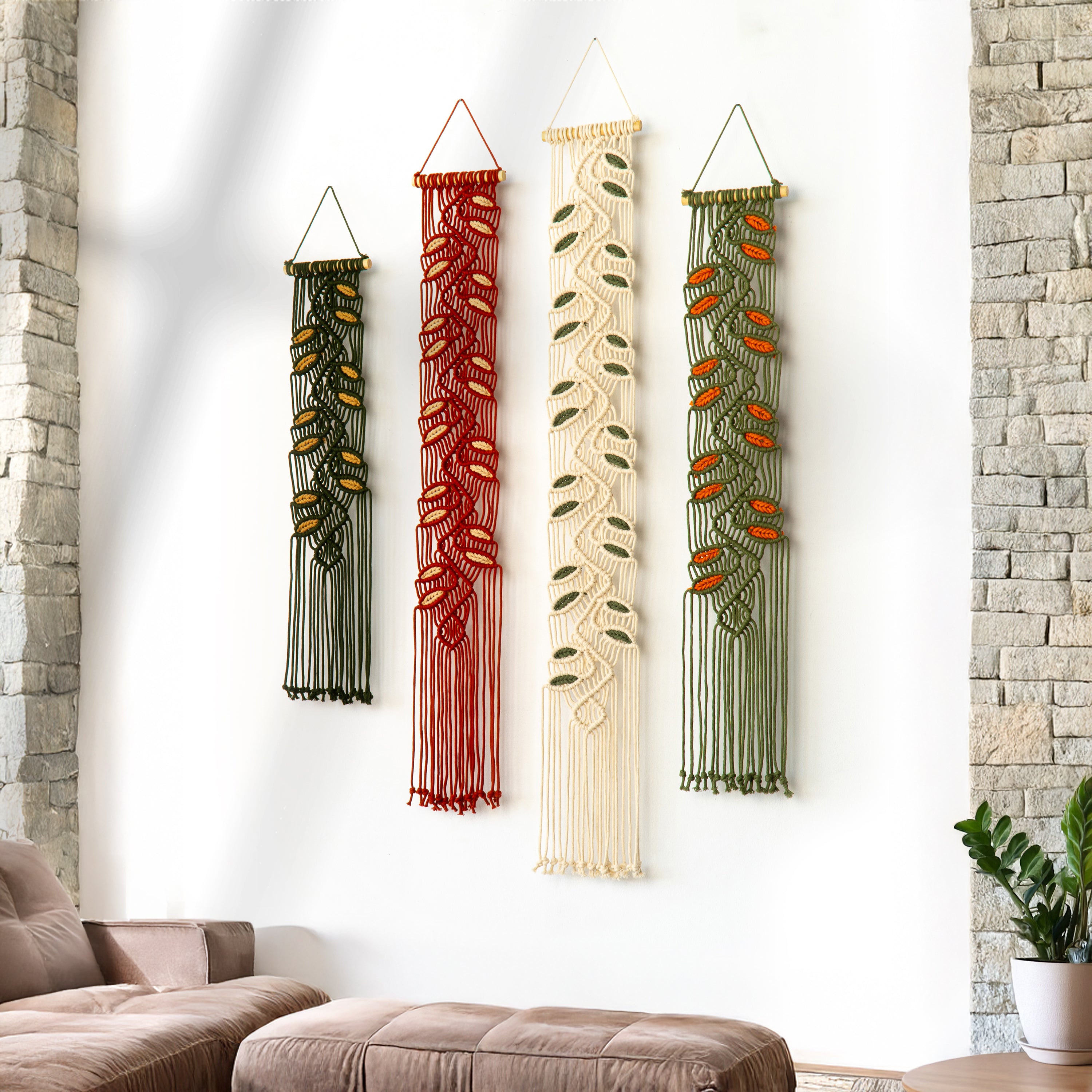 Four macrame wall hangings of different colors hanging on a white wall.