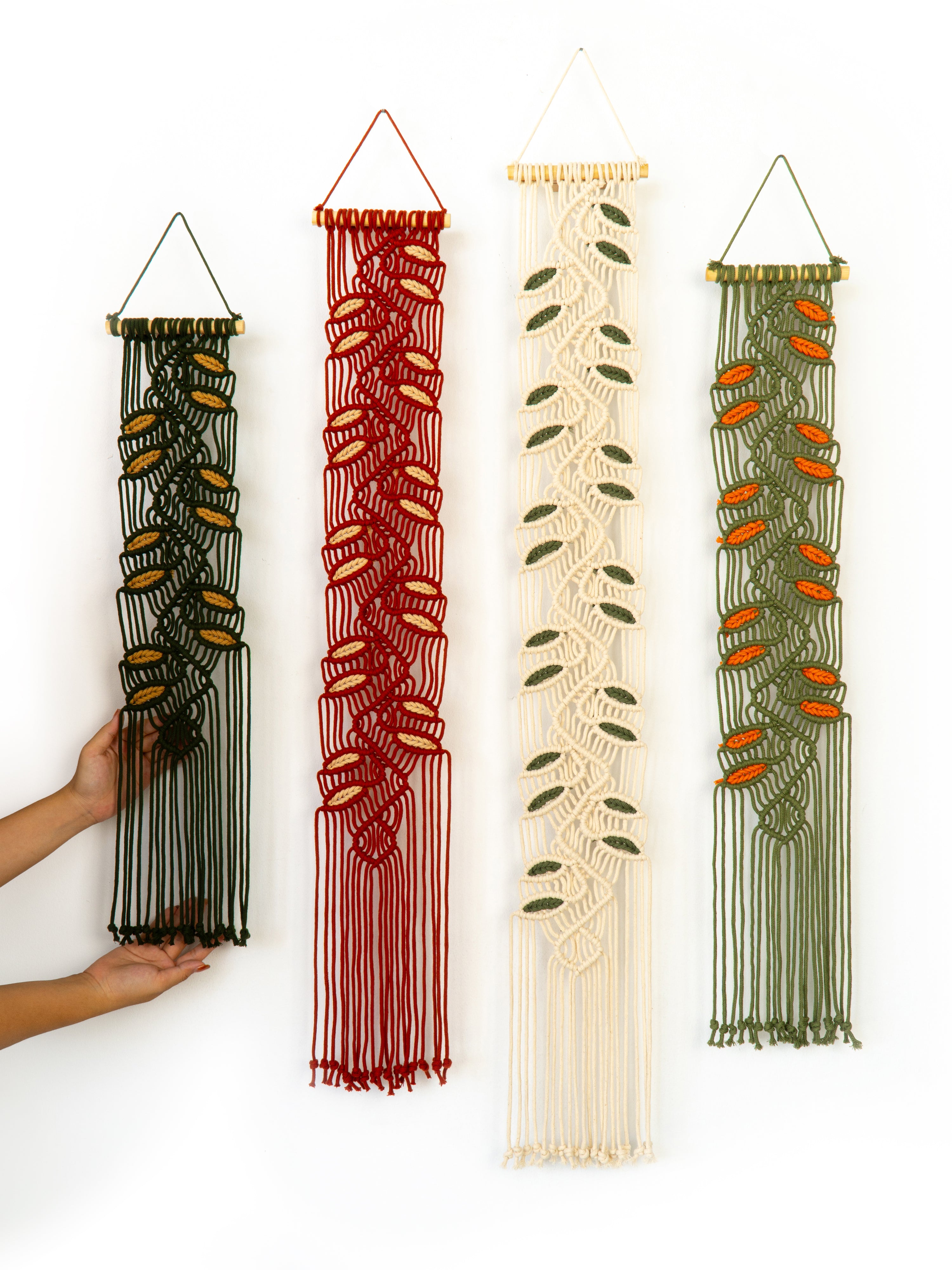 Four macrame wall hangings in different colors on a white background