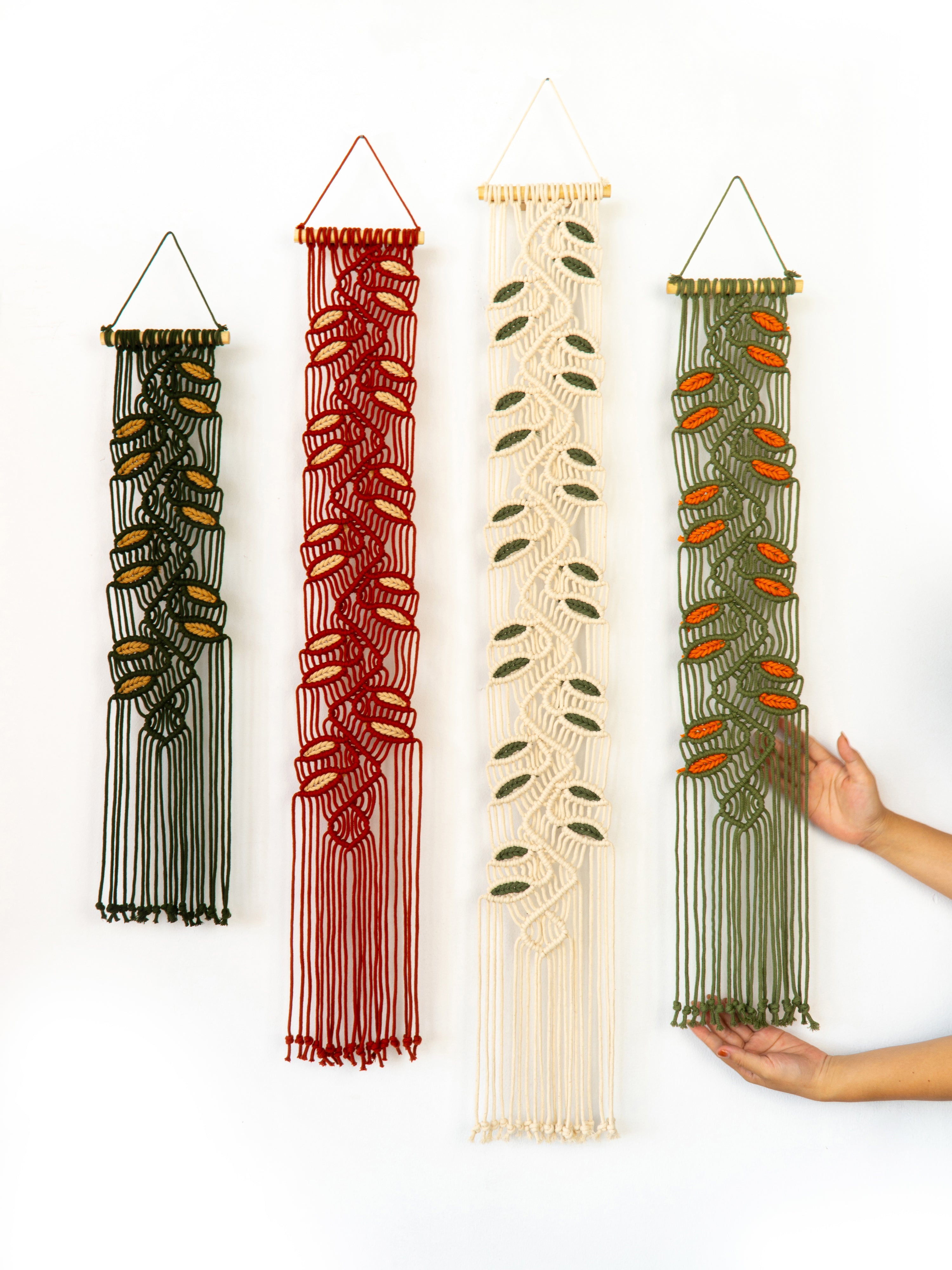 Four macrame wall hangings in different colors on a white background