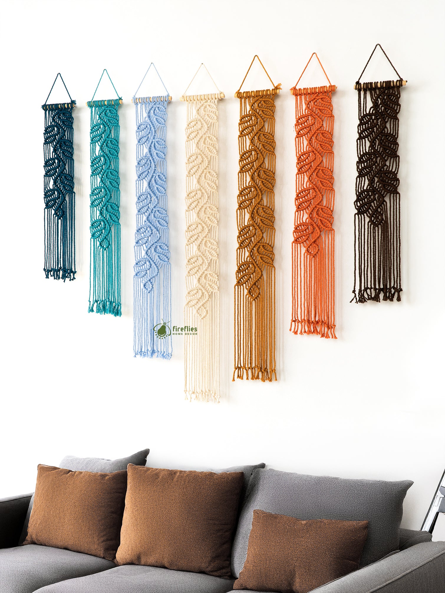 Set of four woven wall hangings in various colors on a white wall.