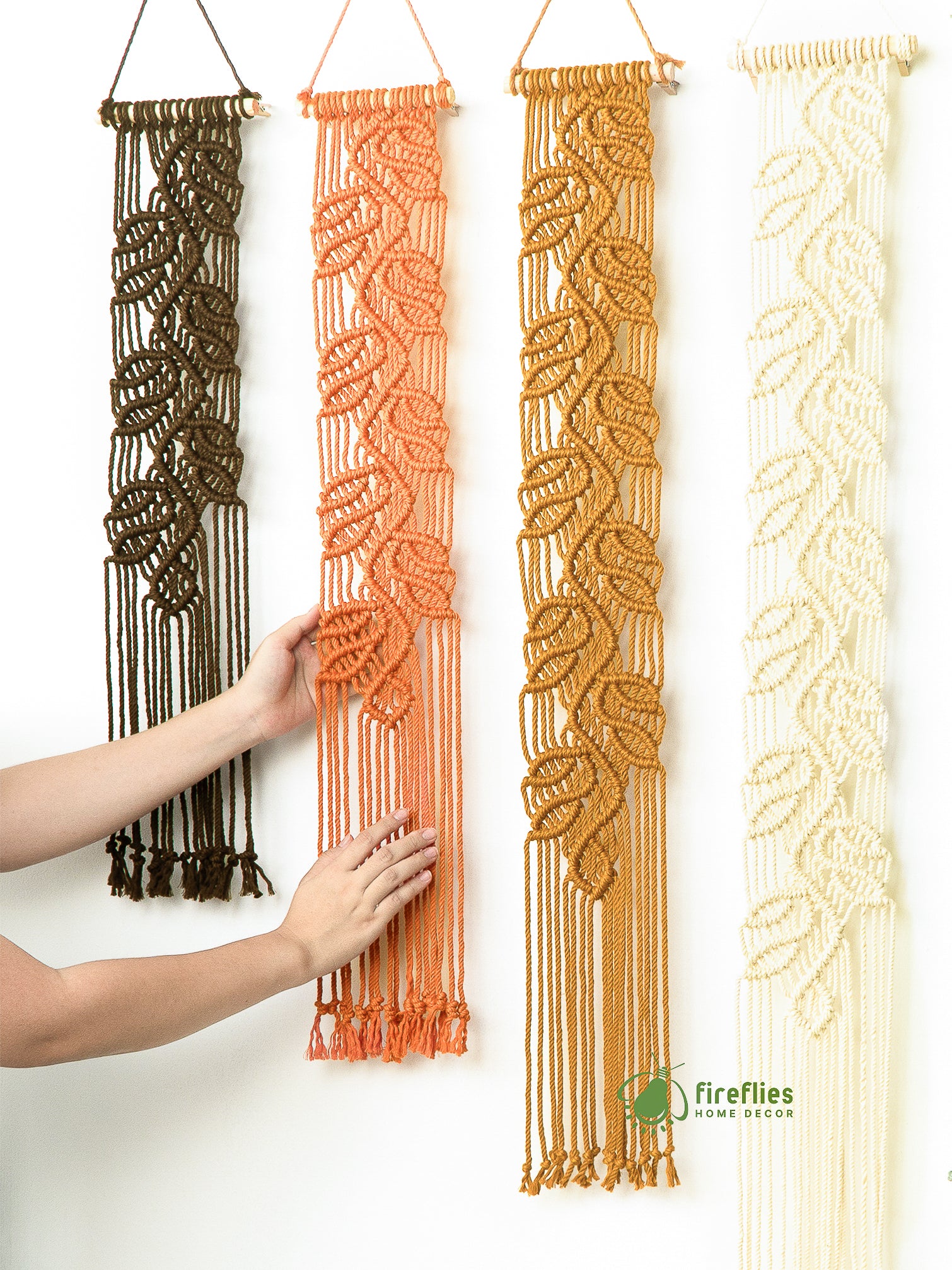 Interior shot showing the macrame leaf collection and surrounding decor, including pillows, plants, and candles.