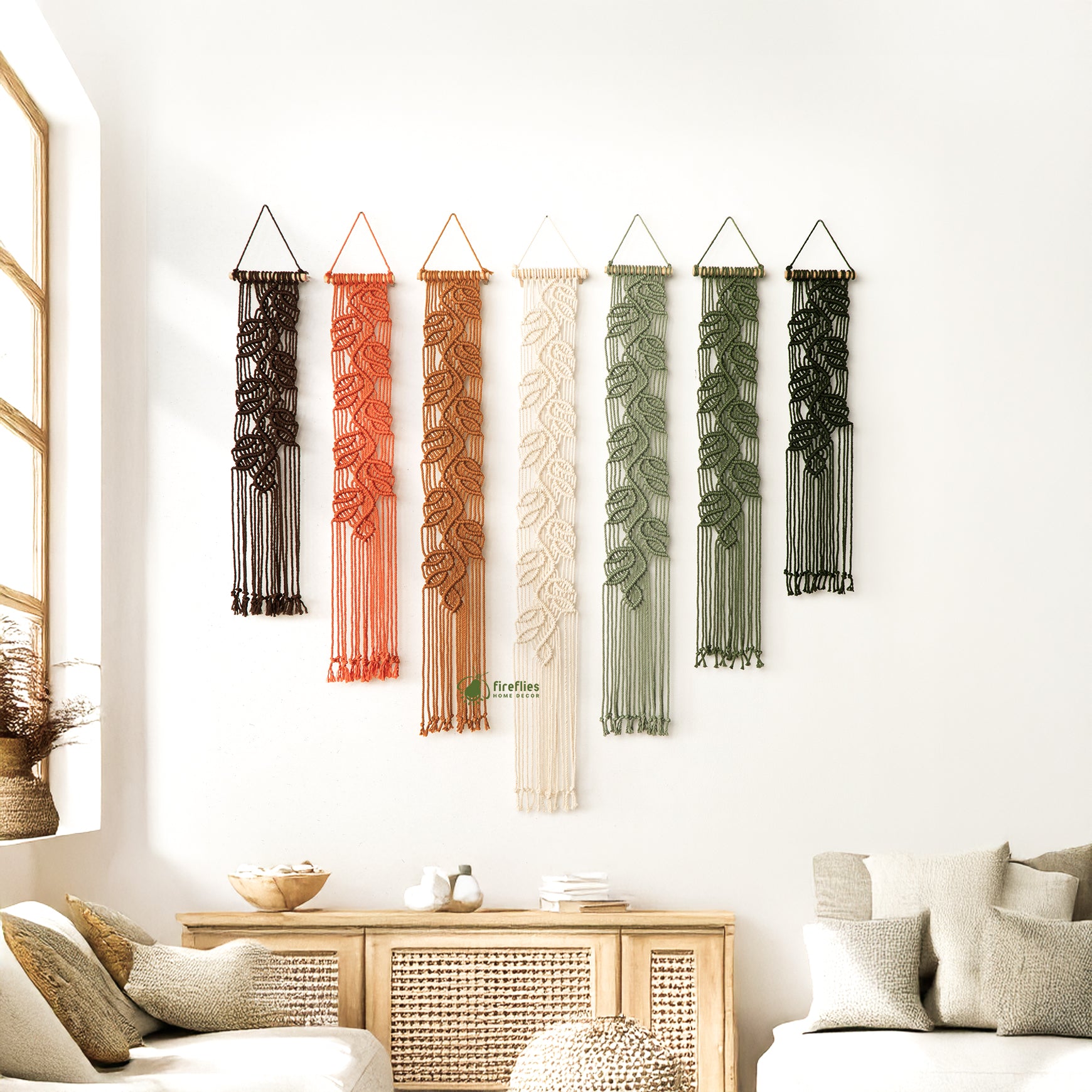 Set of five macrame wall hangings with leaf patterns on a white wall.