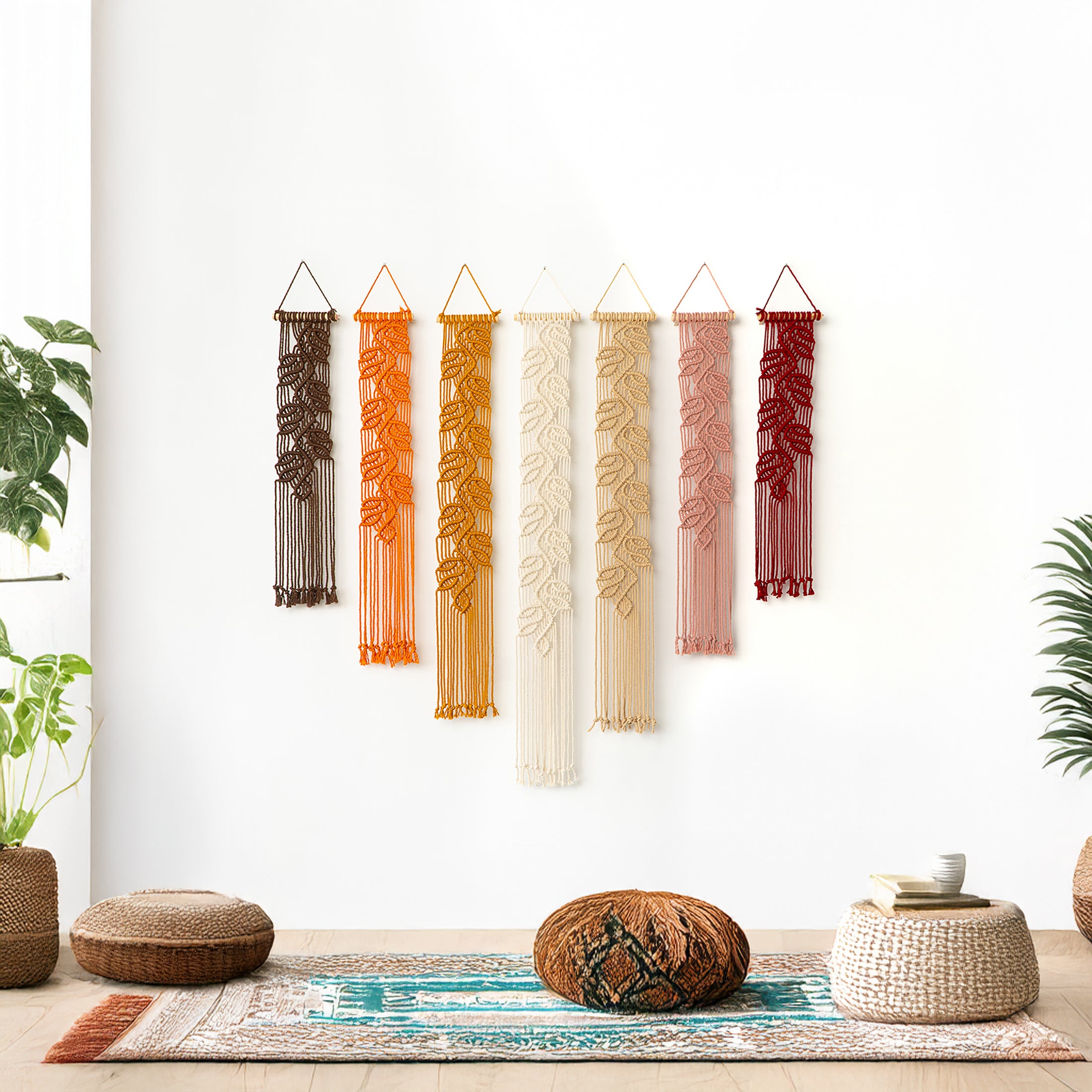 Vertical macrame hangings with long fringe in shades of brown, orange, and cream, being admired or adjusted.