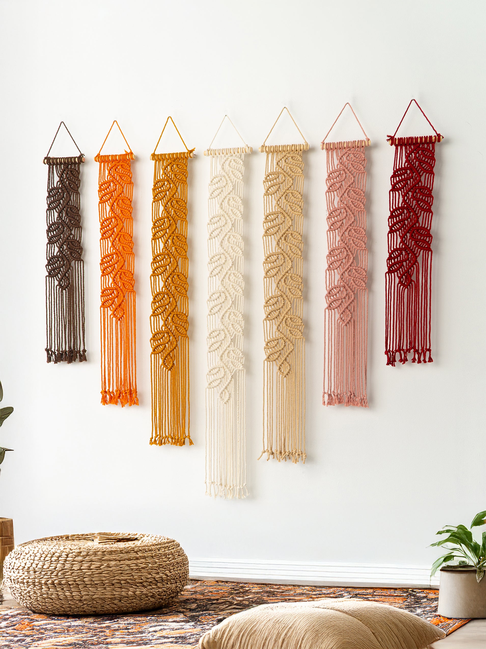 Handmade macrame wall art showing four vertical leaf banners in a warm color progression from dark chocolate to light beige.