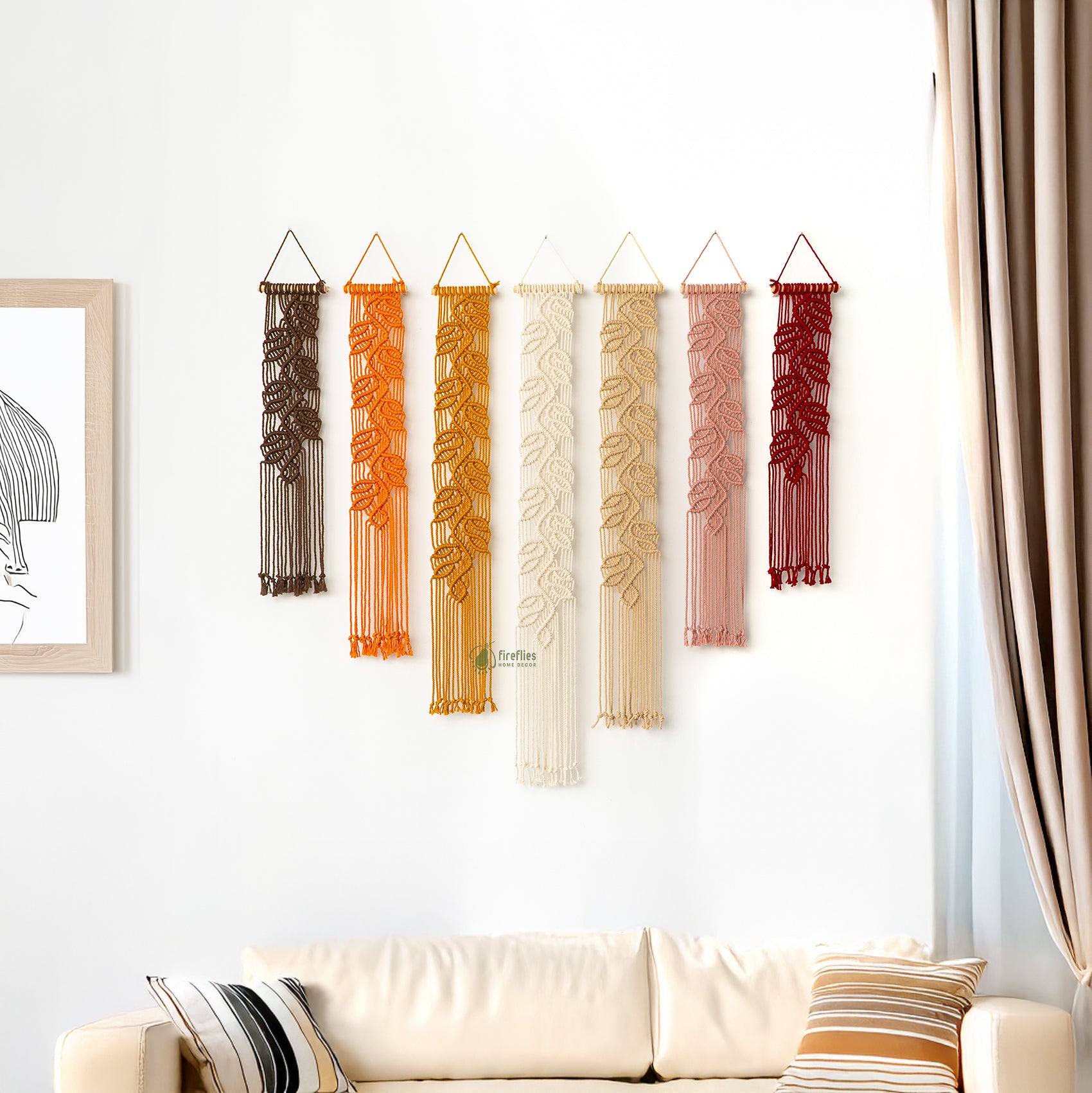 Decorative string wall hangings in various colors on a white wall above a sofa.