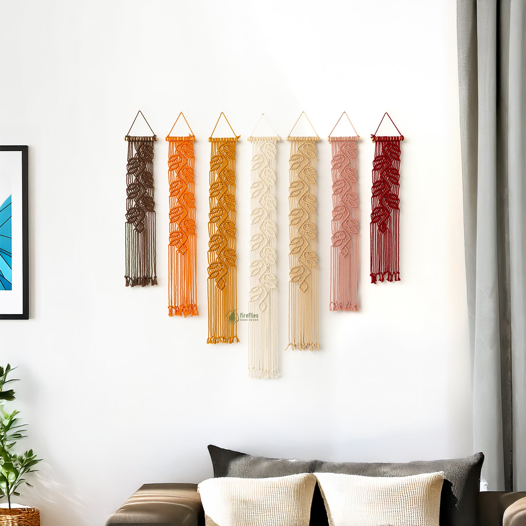 Set of colorful string wall art pieces hanging on a white wall.
