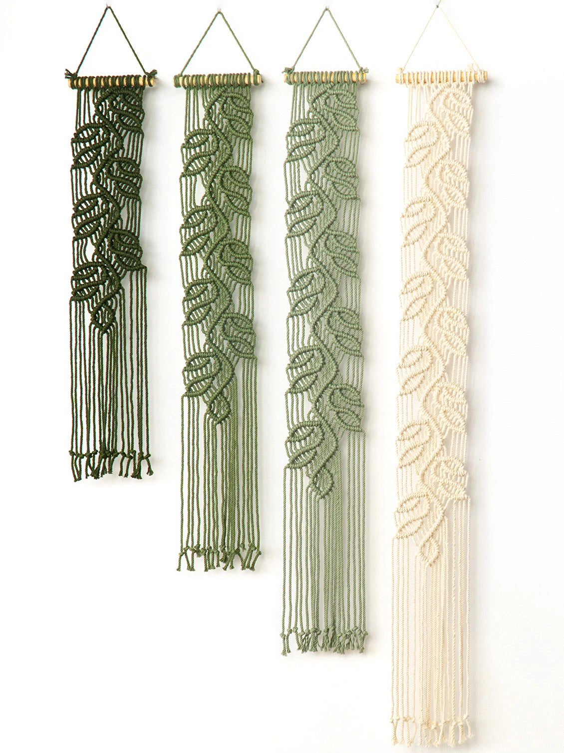 Four macrame wall hangings with leaf patterns in dark green, olive green, sage green, and cream, displayed vertically against a plain white background.