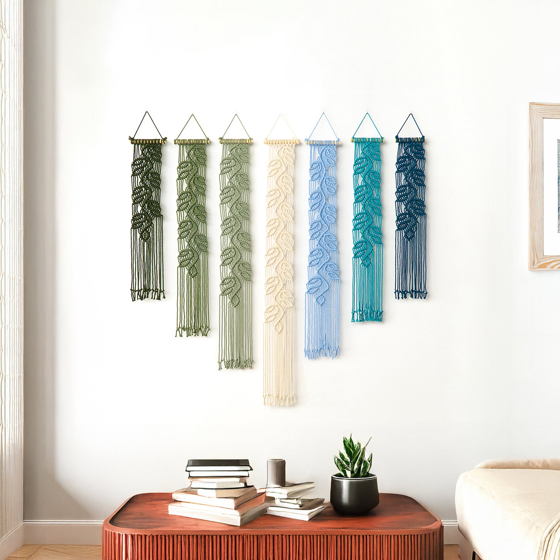 Set of six colorful wall hangings in a room with a wooden table and books.