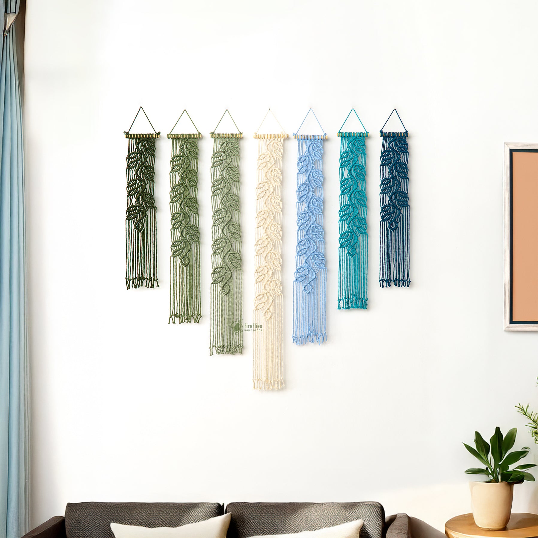 Decorative wall hangings with leaf patterns hanging on a white wall.