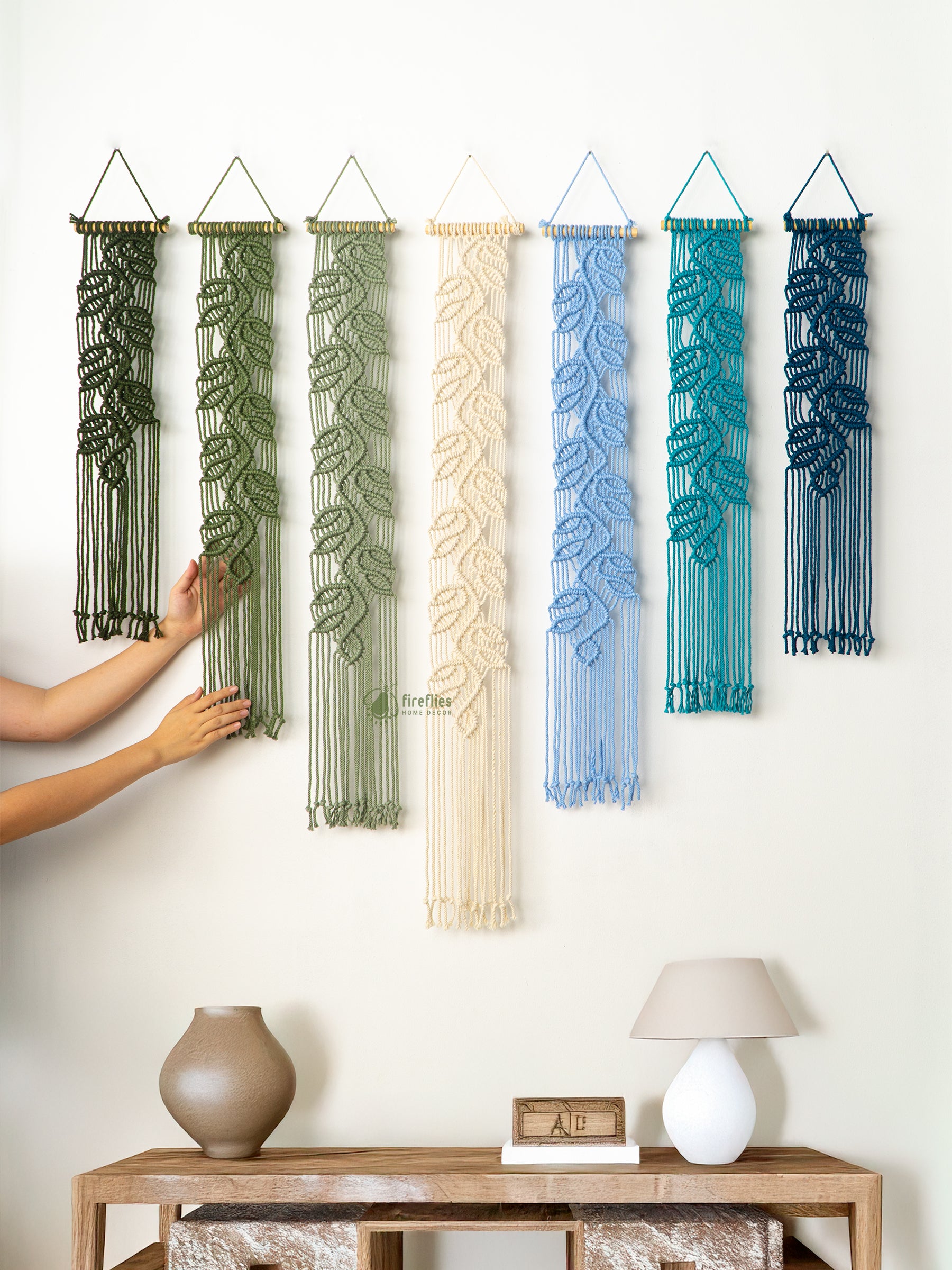 Set of woven wall art pieces in various colors hanging on a white wall.