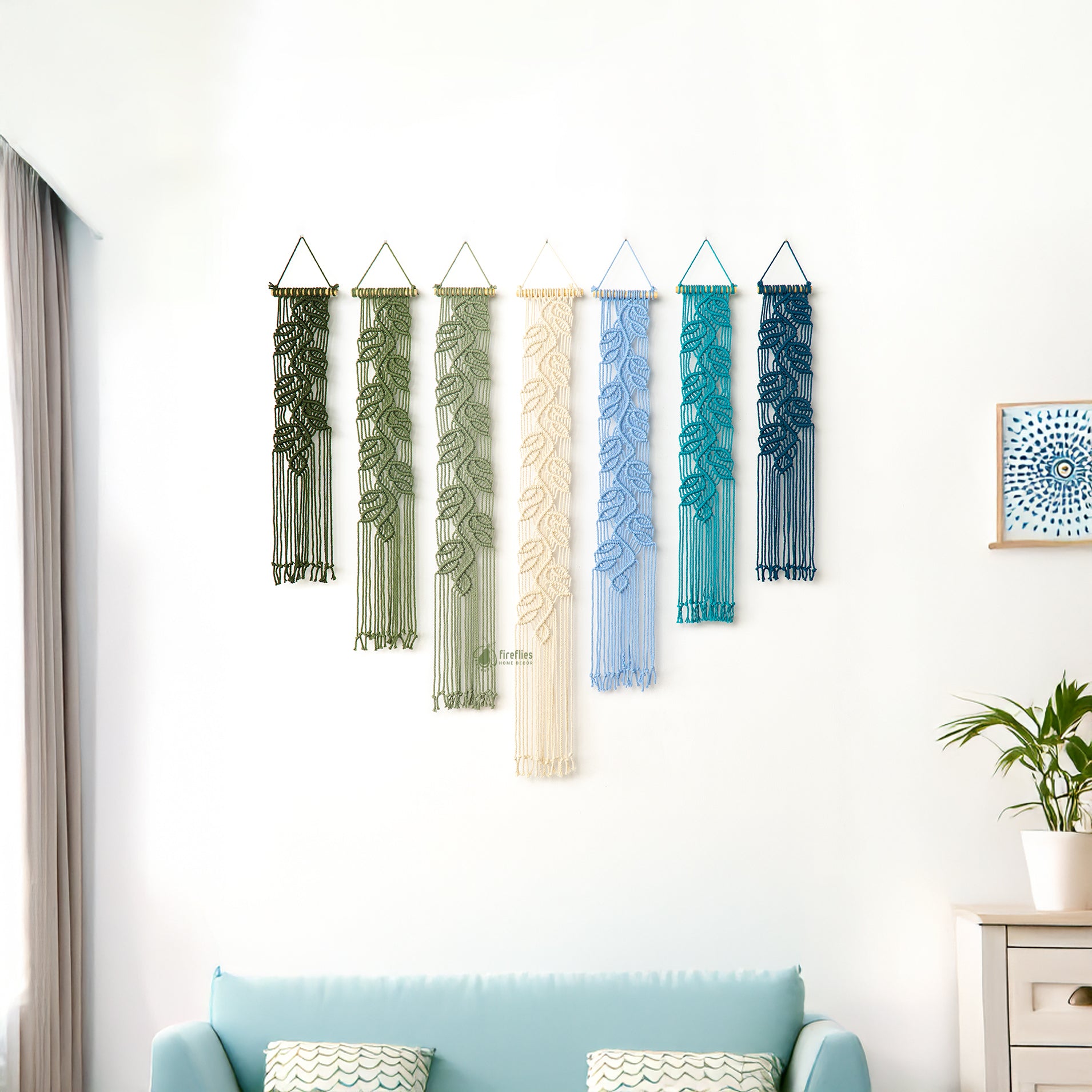 Decorative wall hangings in various colors hanging on a white wall.