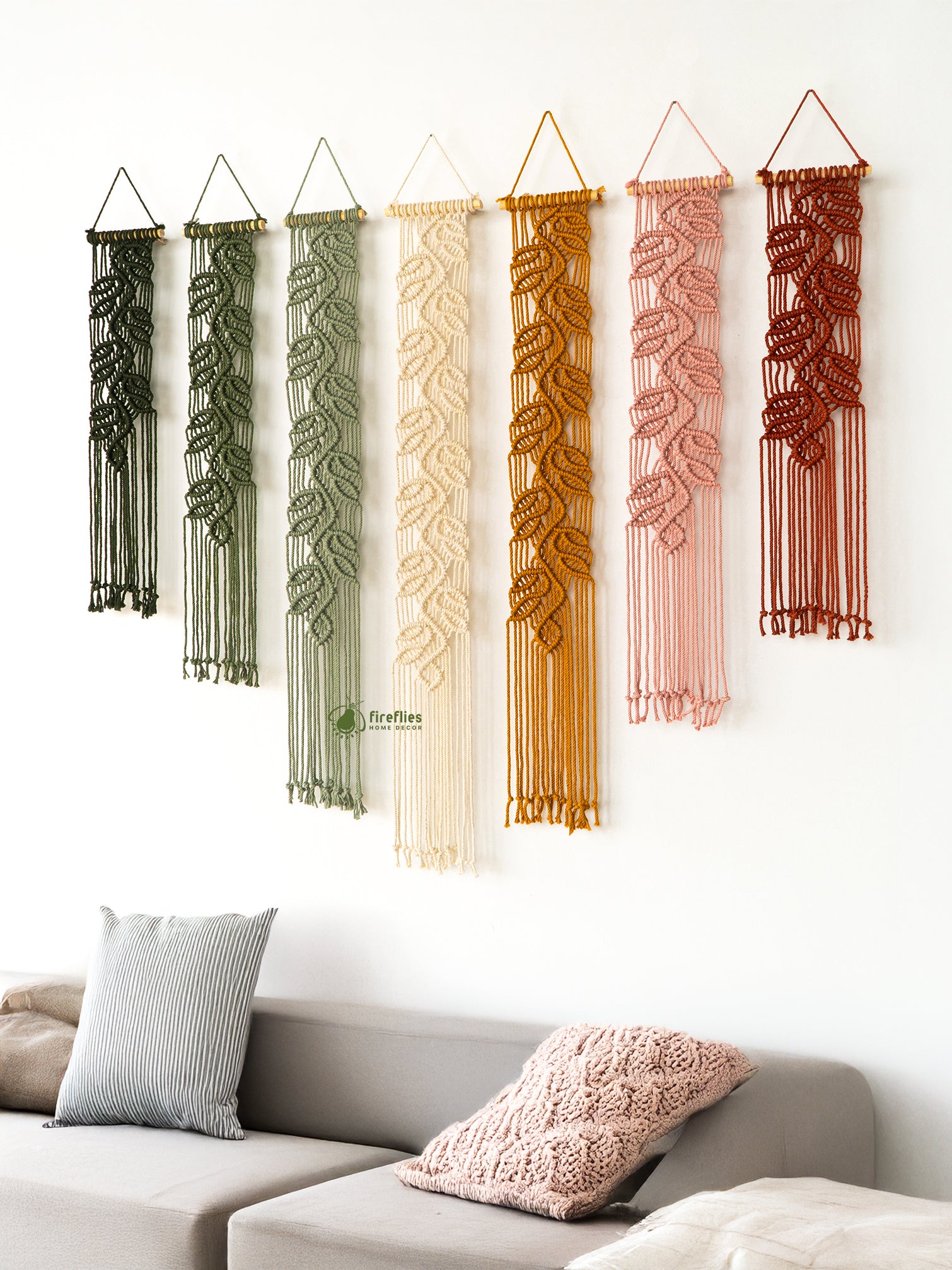 Display of natural-colored macrame wall hangings: two shades of green, cream, mustard yellow, dusty pink, and burnt orange.