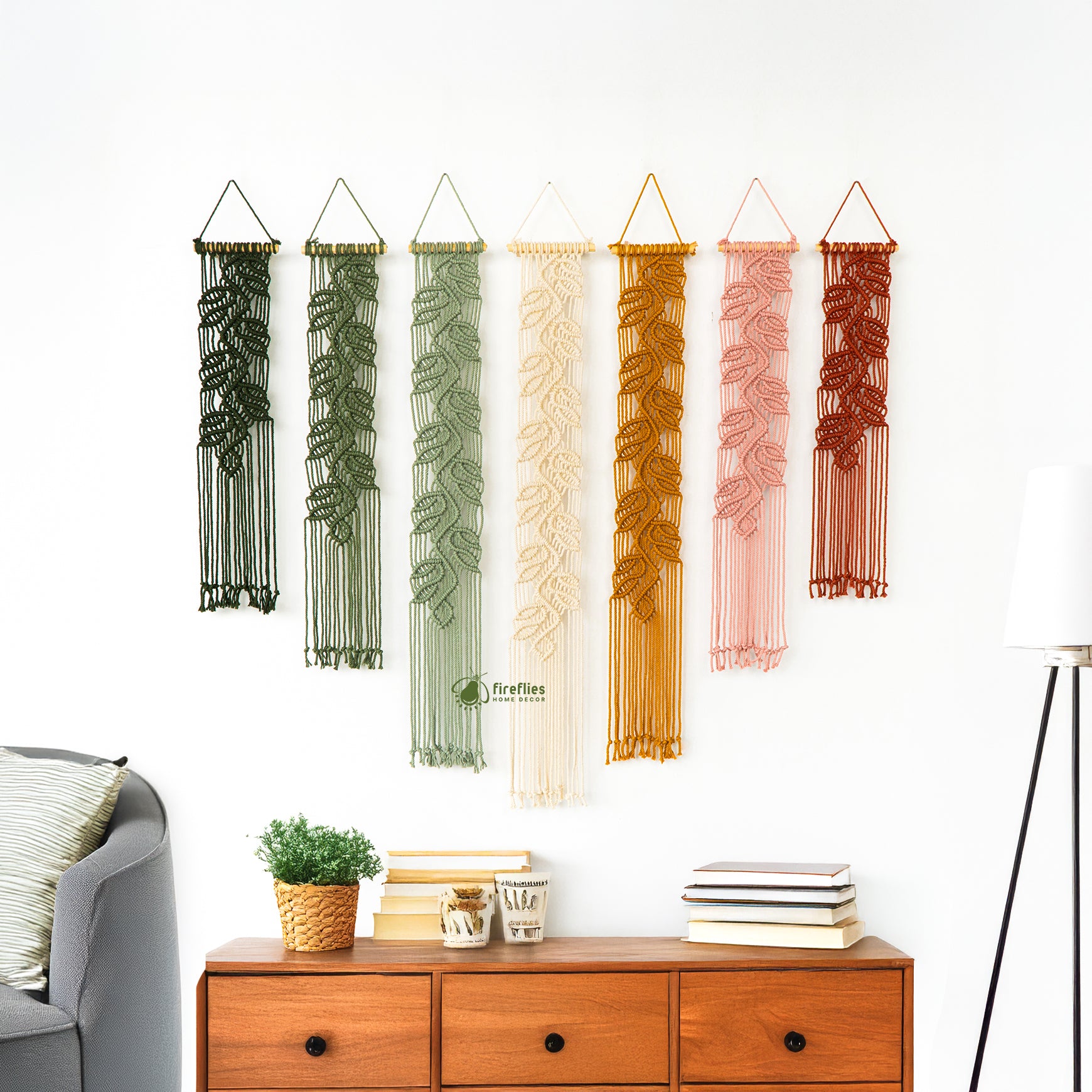 Set of decorative wall hangings with leaf patterns on a white wall above a wooden dresser.