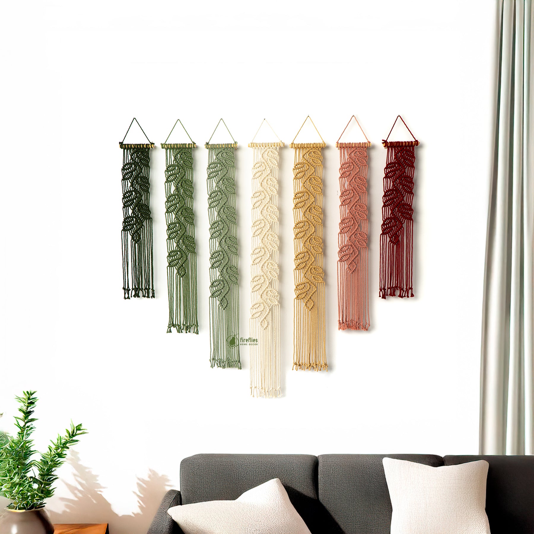Set of six decorative wall hangings with leaf patterns in various colors hanging on a white wall.