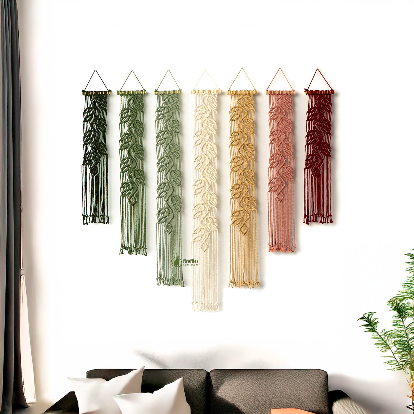 Set of five decorative wall hangings with leaf patterns in various colors on a white wall.