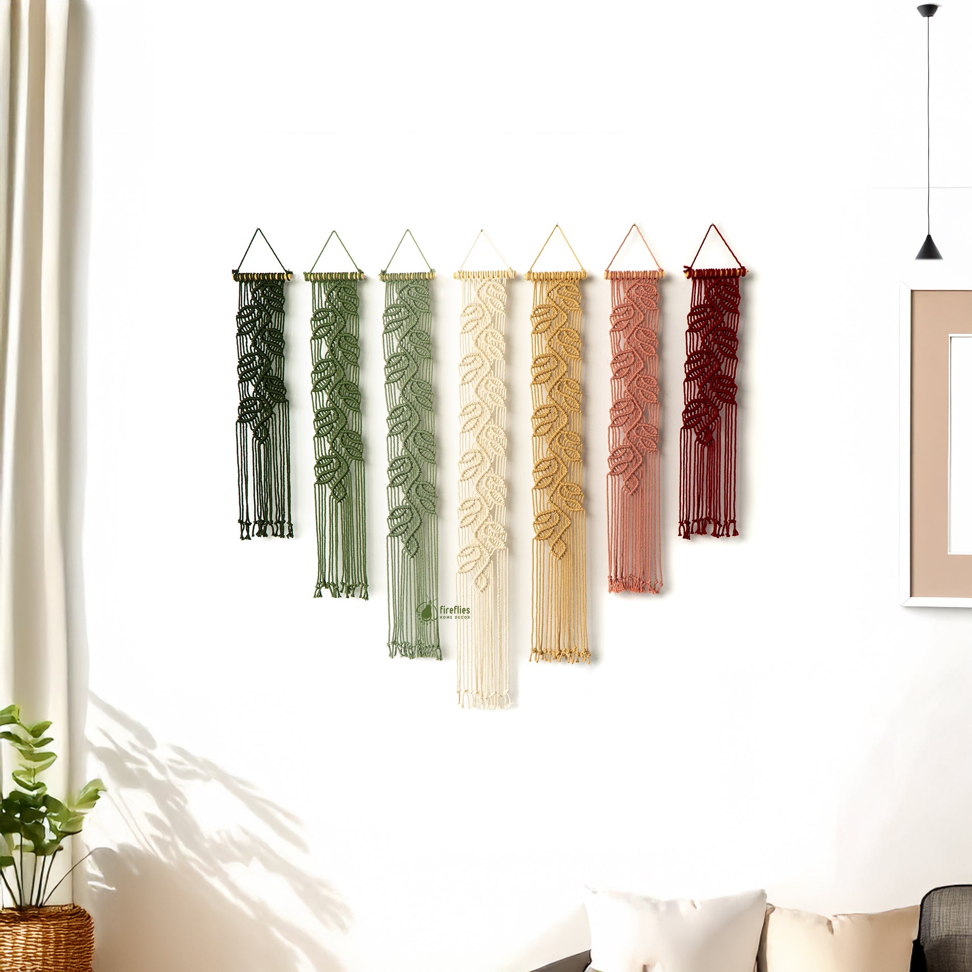 Set of six decorative wall hangings with leaf patterns in various colors hanging on a white wall.