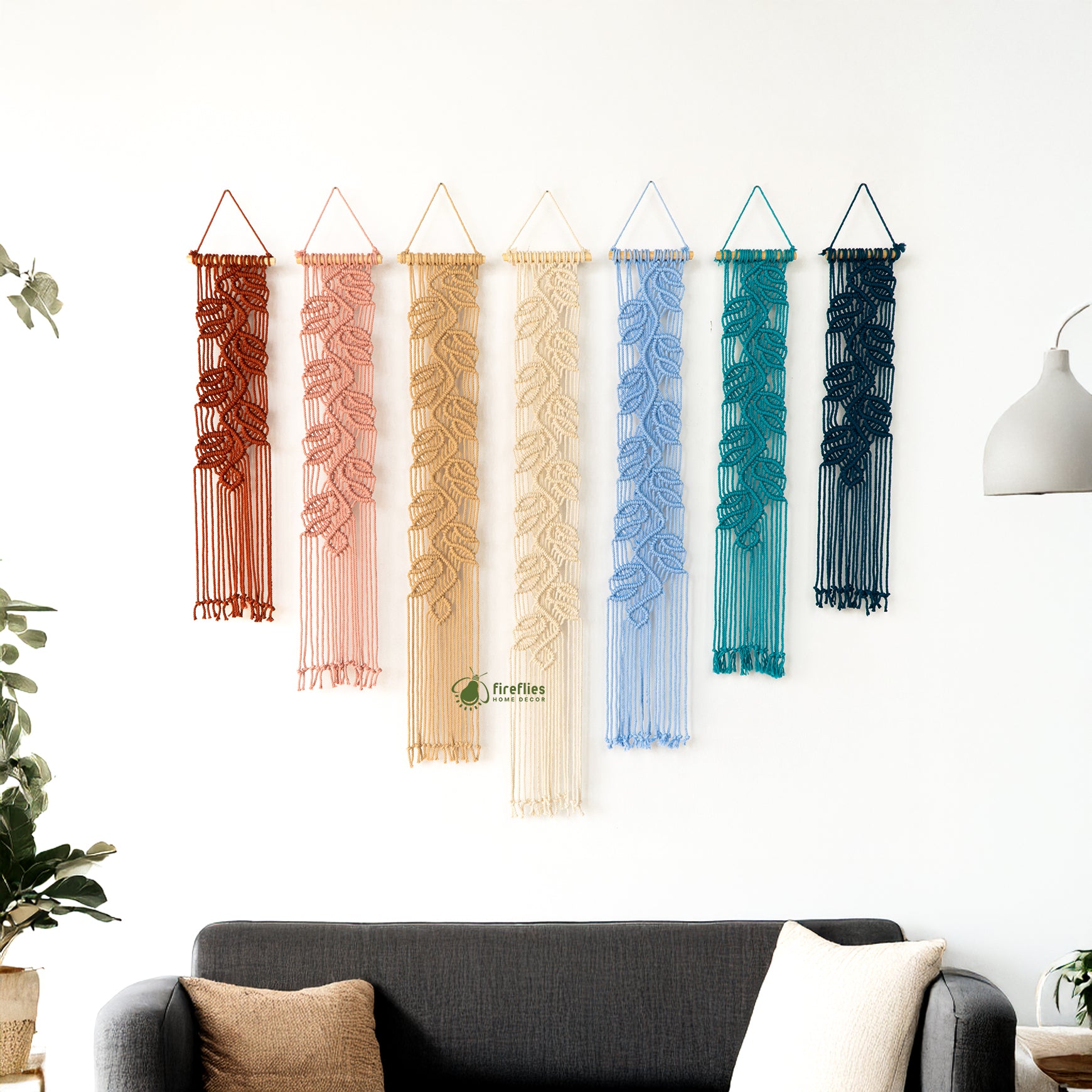 Set of colorful wall hangings on a white wall with a couch and plant in the foreground.
