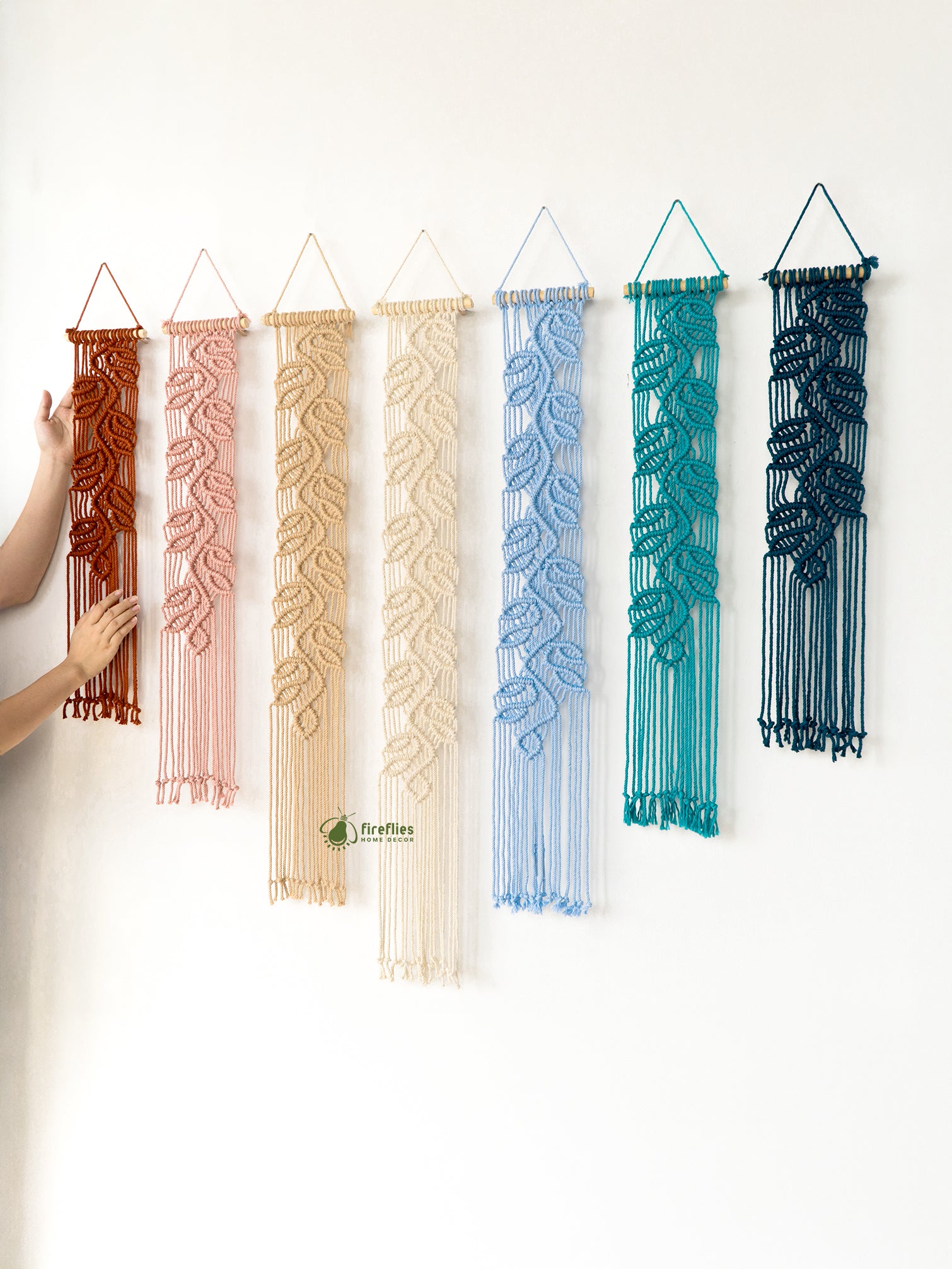 Set of colorful woven wall hangings on a white wall.